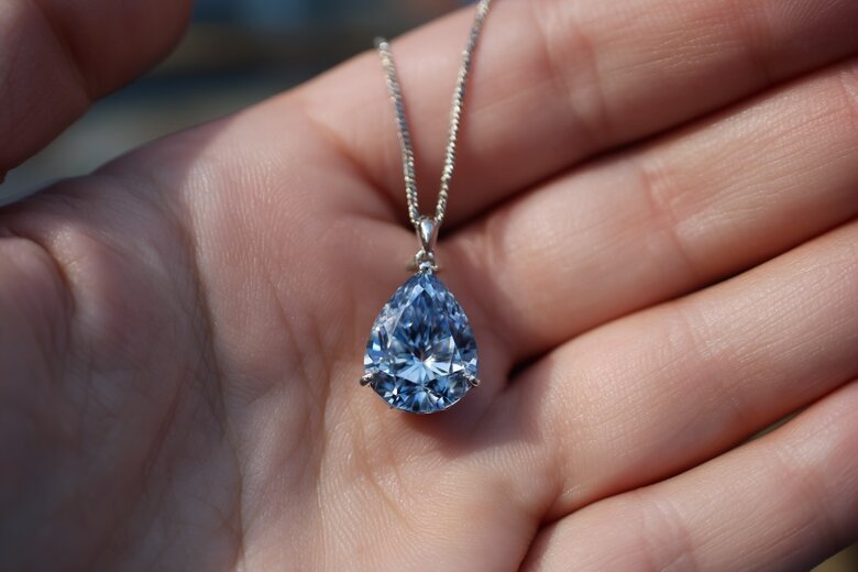 A gentle, respectful image of hands holding a blue memorial diamond pendant